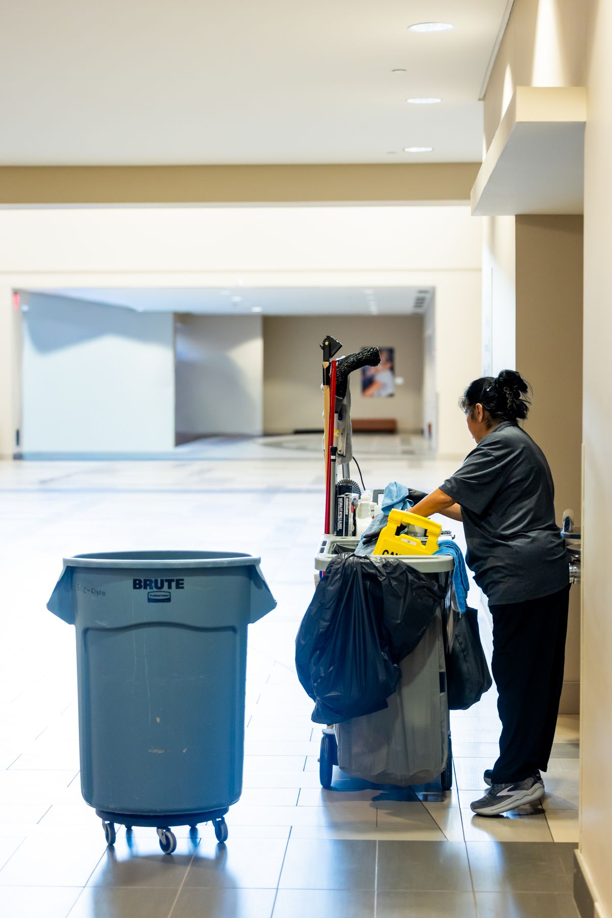 A cleaner with a janitorial cart in the corridor of a commercial building