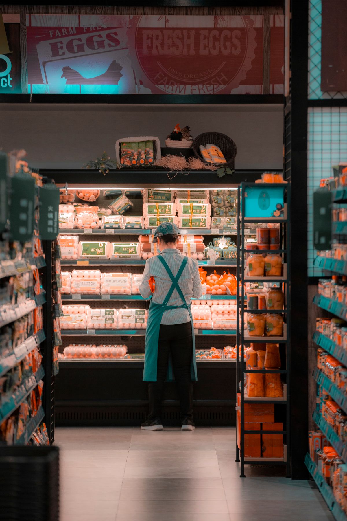 A supermarket worker stocking a chilled shelf